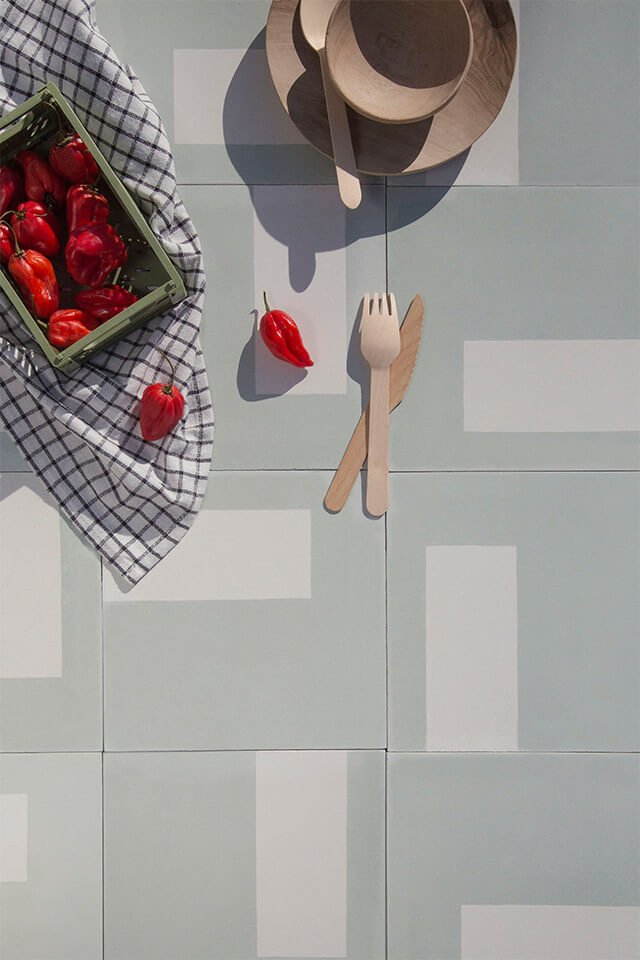 Red chili peppers and wooden cutlery on a soft tone cement tile designed by Glazentile