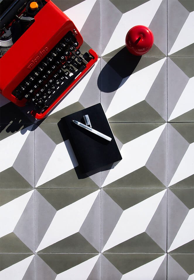 Old school red typewriter and a notebook on a cement tile designed by Glazentile