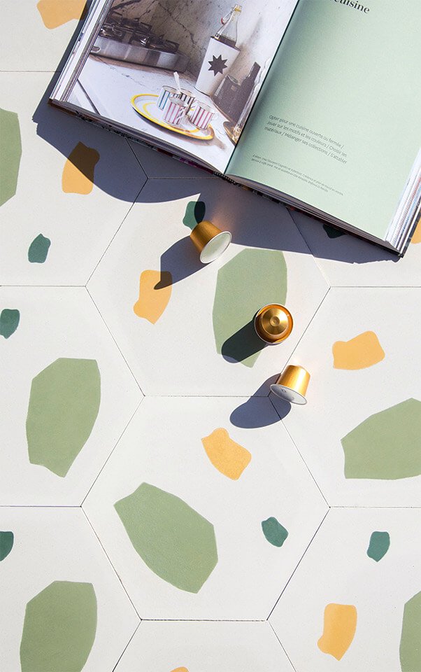 Golden coffee pods and a cooking book on green terrazzo style cement tile from Glazentile