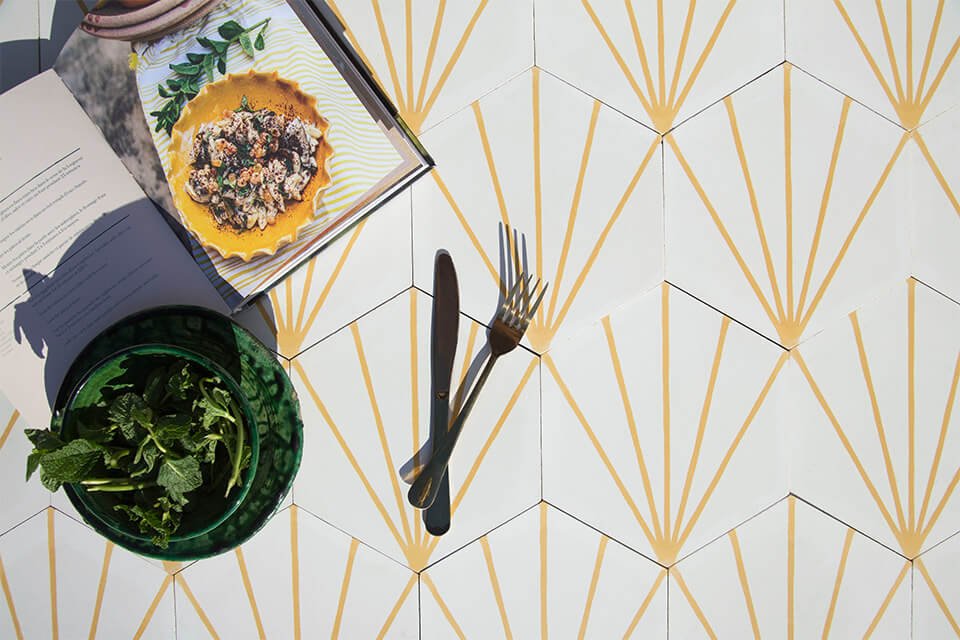 Bowl of greens and a cookbook sit on white and yellow cement tiles from Glazentile