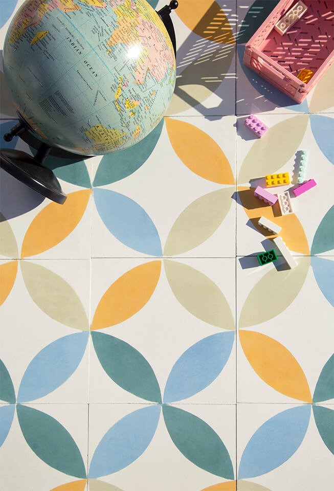 Globe and lego lie on a bright colored cement tile designed by Glazentile