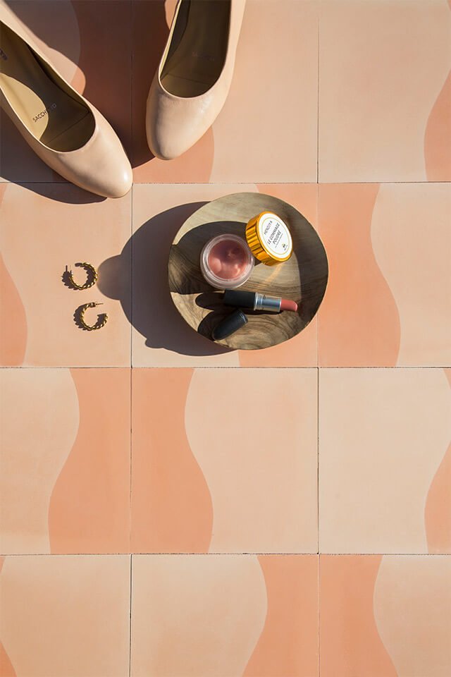 Nude color shoes, cream and lipstick on a nude cement tile designed by Glazentile
